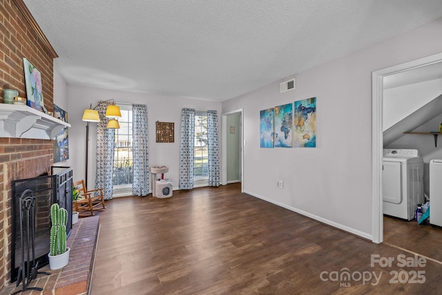 living room with separate washer and dryer, a textured ceiling, dark hardwood / wood-style floors, and a fireplace