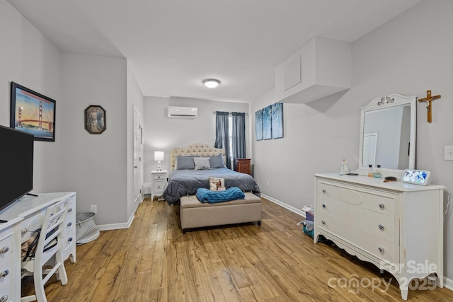 bedroom with a wall mounted AC and light hardwood / wood-style flooring