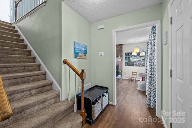 staircase featuring a textured ceiling and hardwood / wood-style flooring