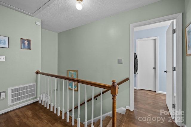 staircase featuring a textured ceiling and wood-type flooring