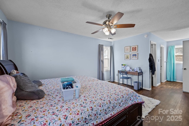 bedroom with ceiling fan, multiple windows, a textured ceiling, and dark hardwood / wood-style flooring