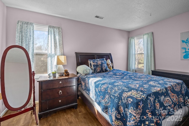 bedroom with dark hardwood / wood-style floors and a textured ceiling