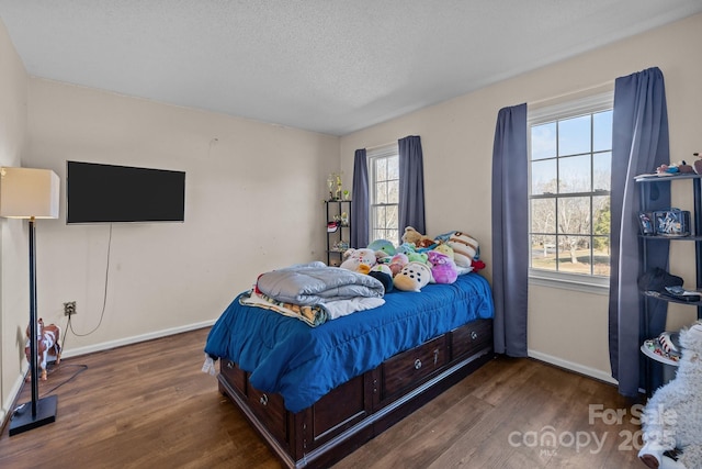 bedroom featuring multiple windows, dark hardwood / wood-style floors, and a textured ceiling