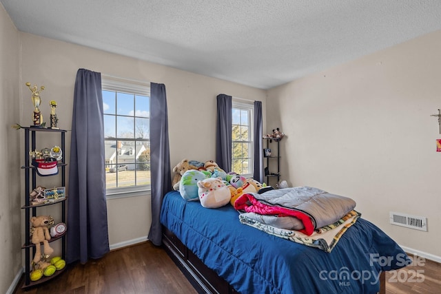 bedroom featuring dark wood-type flooring, multiple windows, and a textured ceiling