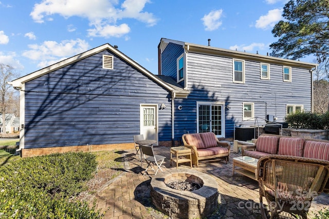 back of property with a patio area and an outdoor living space with a fire pit