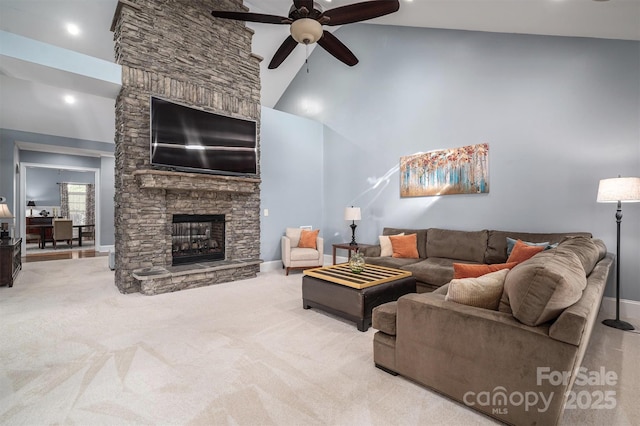 carpeted living room with high vaulted ceiling, ceiling fan, and a stone fireplace