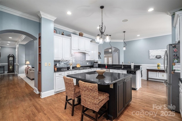 kitchen with a kitchen island, a kitchen bar, stainless steel appliances, sink, and hanging light fixtures