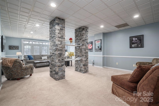 carpeted living room with decorative columns