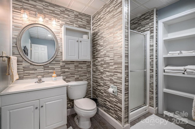 bathroom with toilet, tile walls, built in features, walk in shower, and vanity