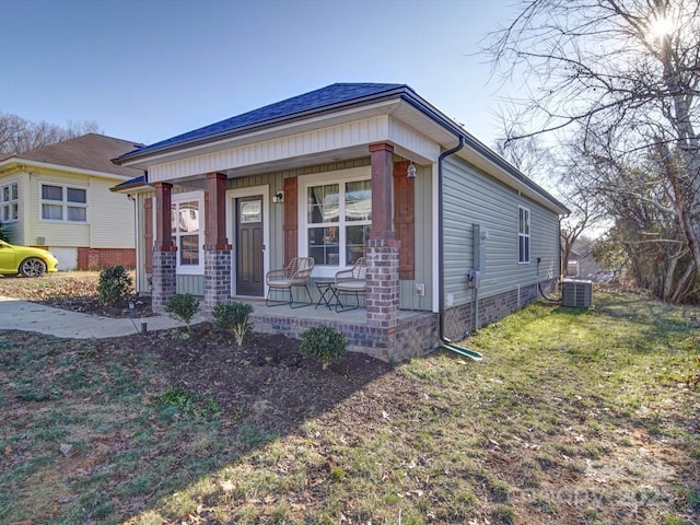 view of front of house with a front lawn, a porch, and central AC