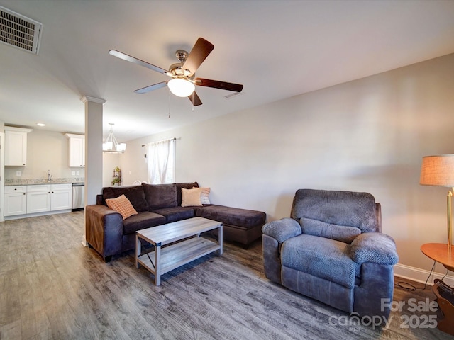 living room with ceiling fan with notable chandelier, hardwood / wood-style floors, and sink