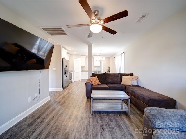 living room with ceiling fan with notable chandelier and hardwood / wood-style floors