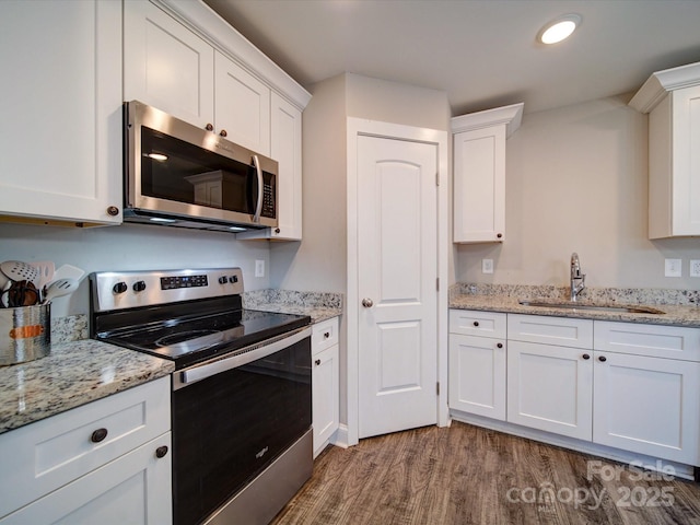 kitchen with sink, wood-type flooring, white cabinets, and stainless steel appliances