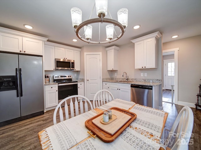 kitchen featuring an inviting chandelier, white cabinetry, stainless steel appliances, light stone counters, and sink