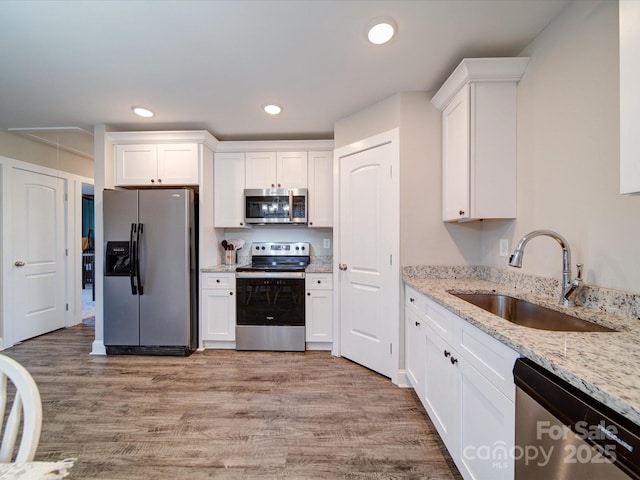 kitchen featuring white cabinets, sink, light stone counters, and stainless steel appliances