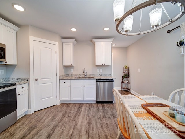 kitchen featuring appliances with stainless steel finishes, white cabinets, a chandelier, light hardwood / wood-style flooring, and sink