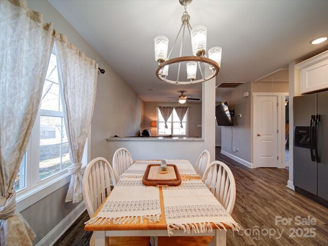 dining area featuring ceiling fan with notable chandelier, a wealth of natural light, and dark hardwood / wood-style flooring