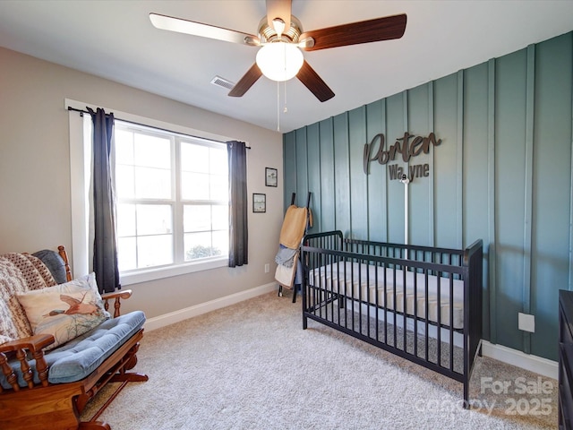 carpeted bedroom featuring ceiling fan and a nursery area