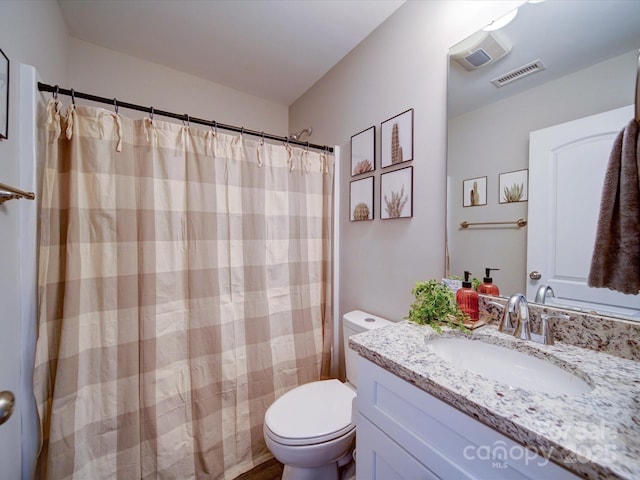 bathroom with toilet, vanity, and walk in shower