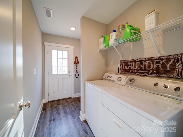 clothes washing area featuring washer and clothes dryer and dark hardwood / wood-style flooring