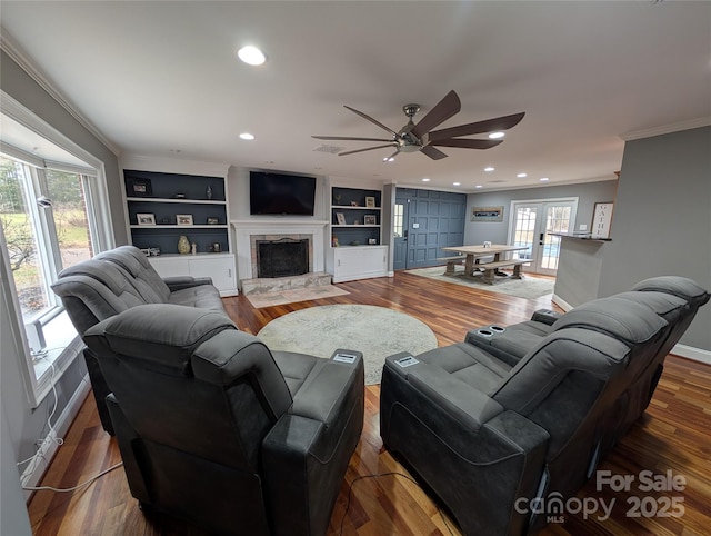 living room featuring ceiling fan, built in shelves, french doors, and a healthy amount of sunlight