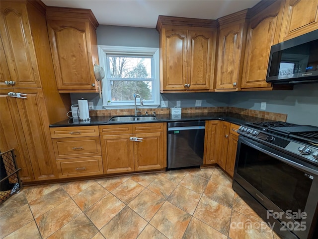 kitchen with dishwasher, dark stone countertops, sink, gas range oven, and light tile patterned floors