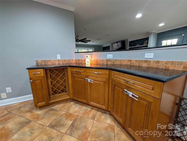 kitchen featuring ceiling fan, dark stone countertops, and crown molding