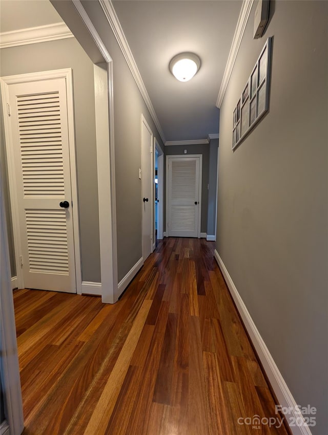 hall with dark wood-type flooring and ornamental molding