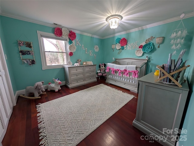 bedroom featuring crown molding, dark wood-type flooring, and a crib