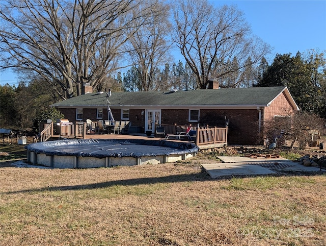 back of property featuring a pool side deck and a yard