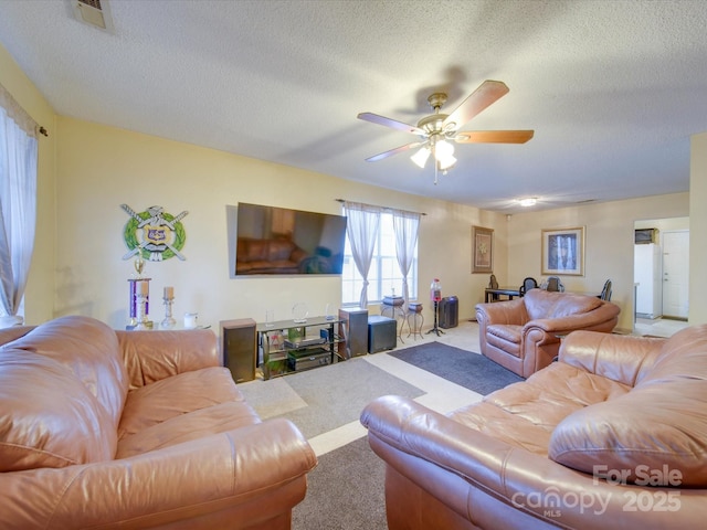 carpeted living room with ceiling fan and a textured ceiling