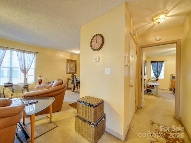 hallway with a textured ceiling and light carpet