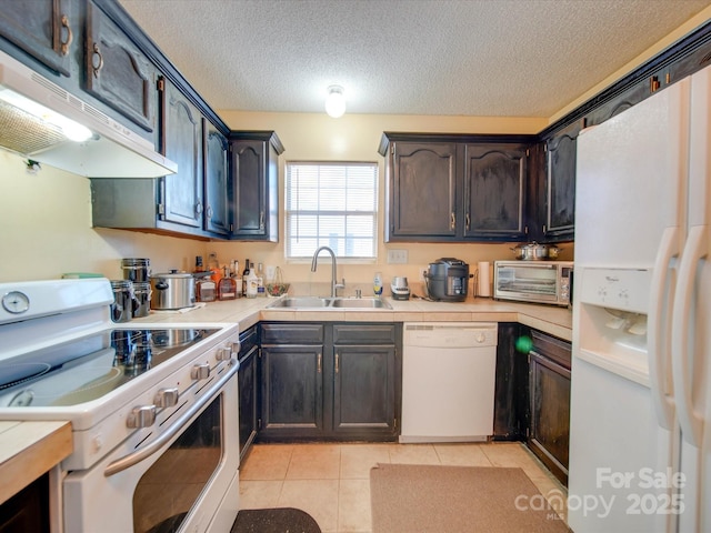 kitchen with light tile patterned floors, sink, white appliances, and a textured ceiling