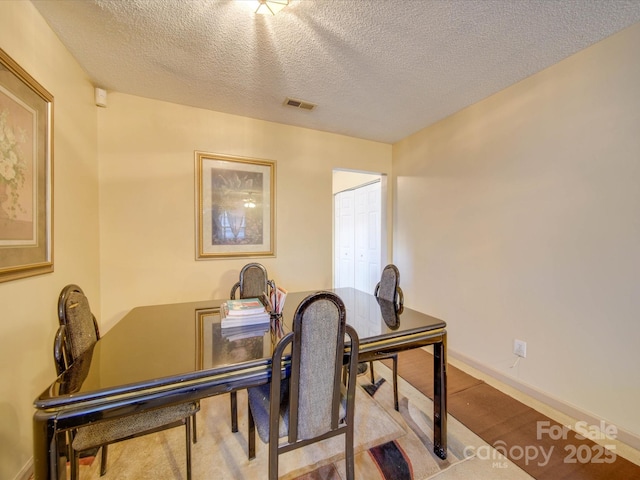 dining space featuring a textured ceiling and light hardwood / wood-style flooring