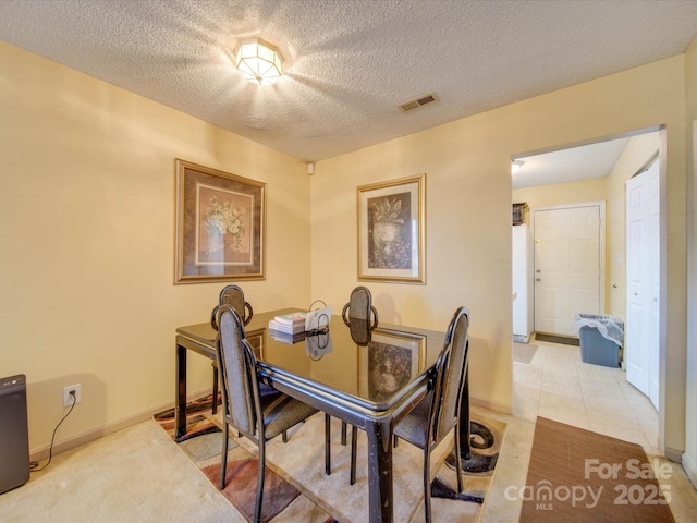 dining area featuring light tile patterned floors and a textured ceiling