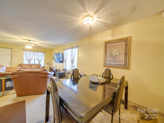 carpeted dining area featuring ceiling fan and a textured ceiling