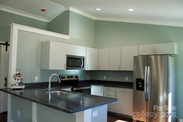 kitchen featuring a barn door, sink, appliances with stainless steel finishes, ornamental molding, and white cabinets