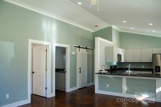 kitchen with stainless steel appliances, sink, kitchen peninsula, ornamental molding, and a barn door