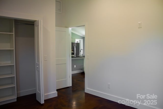 unfurnished bedroom featuring stainless steel fridge with ice dispenser, a closet, and vaulted ceiling