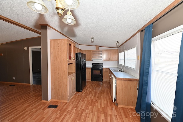 kitchen featuring vaulted ceiling, black appliances, sink, light hardwood / wood-style flooring, and ornamental molding