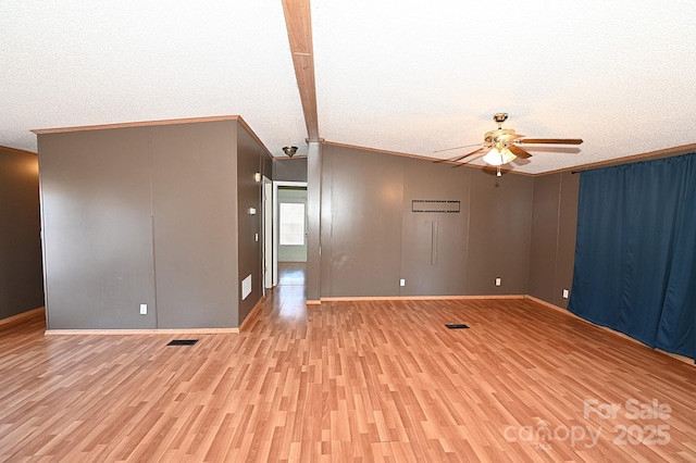 spare room with ceiling fan, vaulted ceiling, a textured ceiling, and light hardwood / wood-style floors