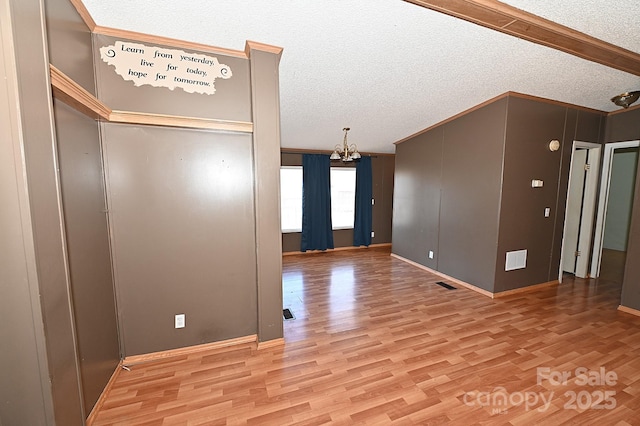 unfurnished room featuring light hardwood / wood-style floors, a textured ceiling, and a notable chandelier