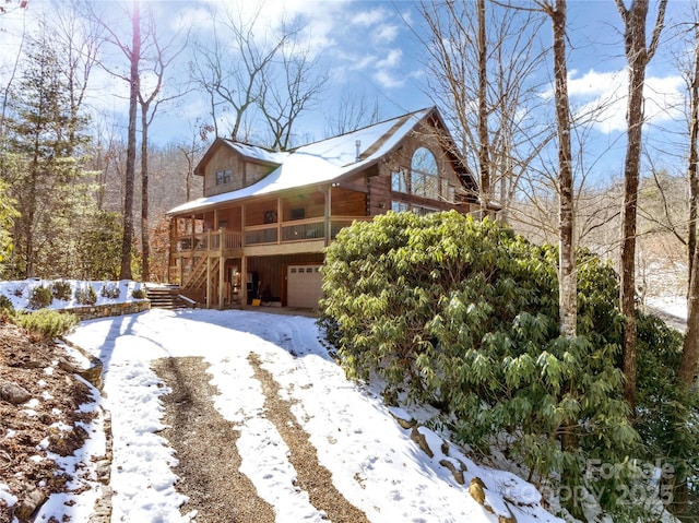 snow covered property featuring a sunroom and a garage