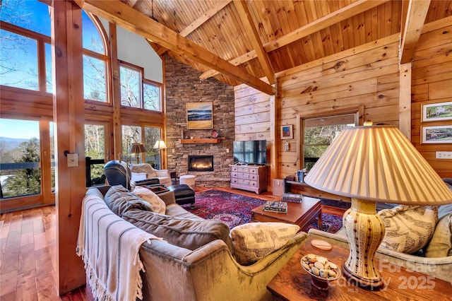 living room with a fireplace, wood walls, hardwood / wood-style floors, beamed ceiling, and high vaulted ceiling