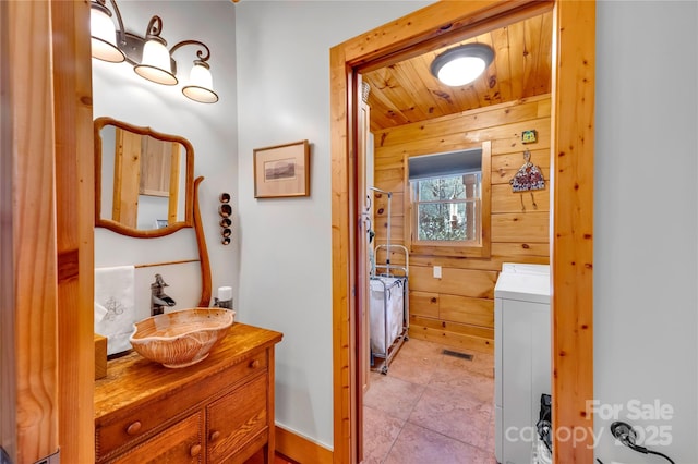 bathroom featuring washer / dryer, wooden ceiling, wooden walls, and vanity