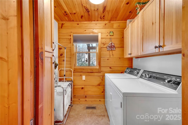 washroom featuring cabinets, wood walls, washing machine and clothes dryer, light tile patterned floors, and wooden ceiling