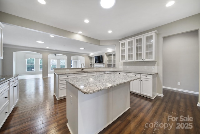 kitchen featuring tasteful backsplash, a center island, kitchen peninsula, sink, and white cabinets