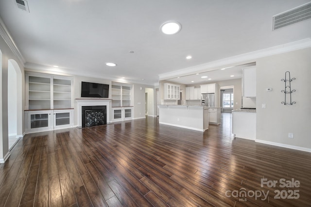 unfurnished living room with ornamental molding, built in features, and dark hardwood / wood-style flooring