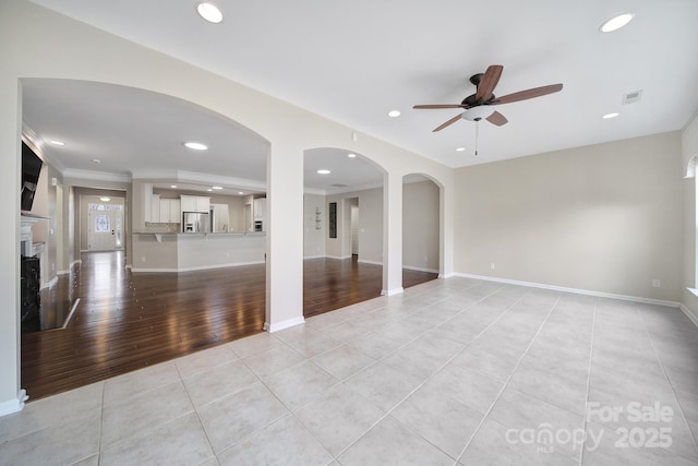 unfurnished living room with ceiling fan, light tile patterned flooring, and ornamental molding