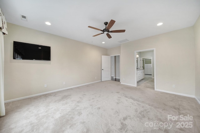 unfurnished bedroom featuring ceiling fan, light colored carpet, and ensuite bath